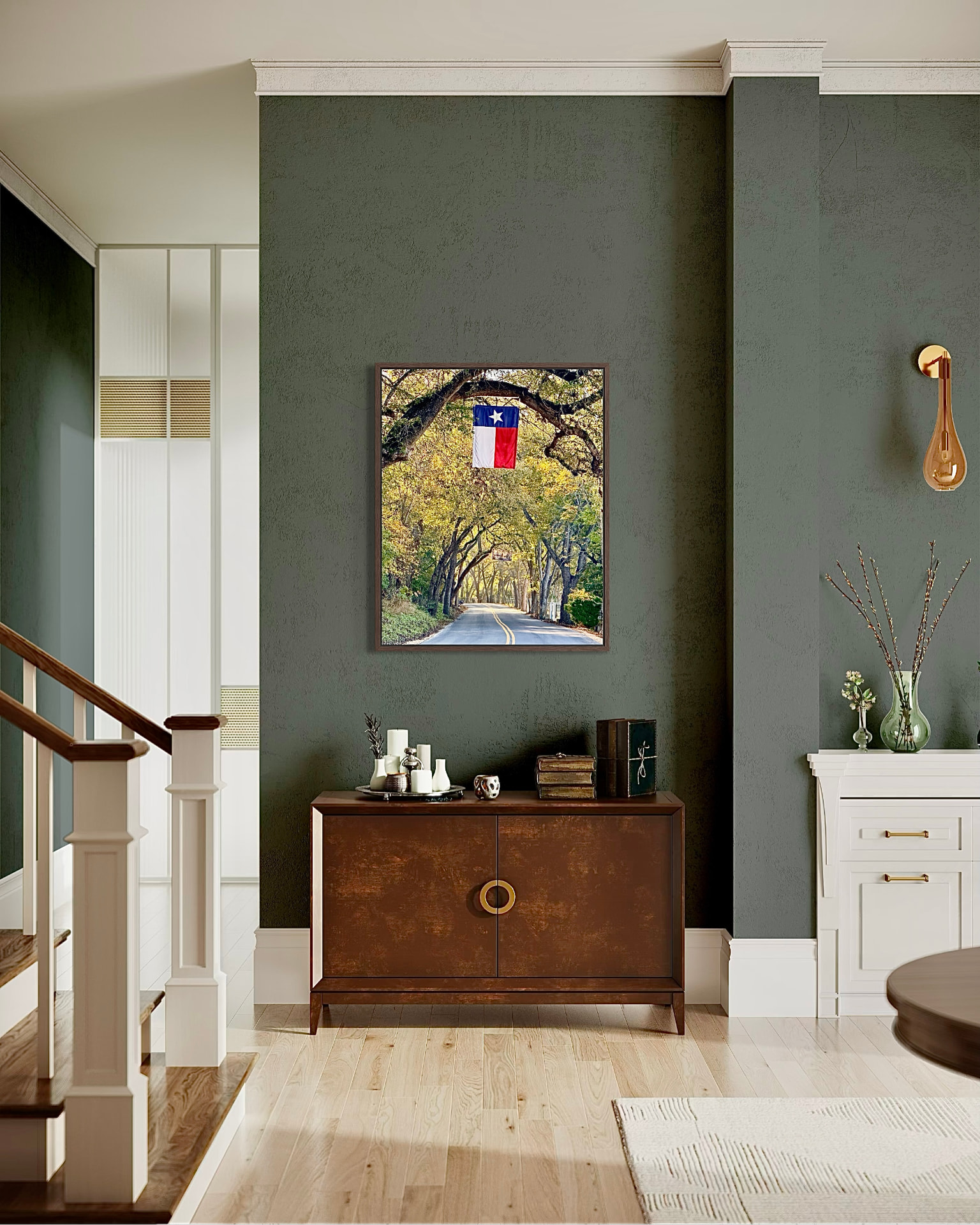 Framed Texas flag beneath a live oak canopy hung above a wood console on a dark green entry wall